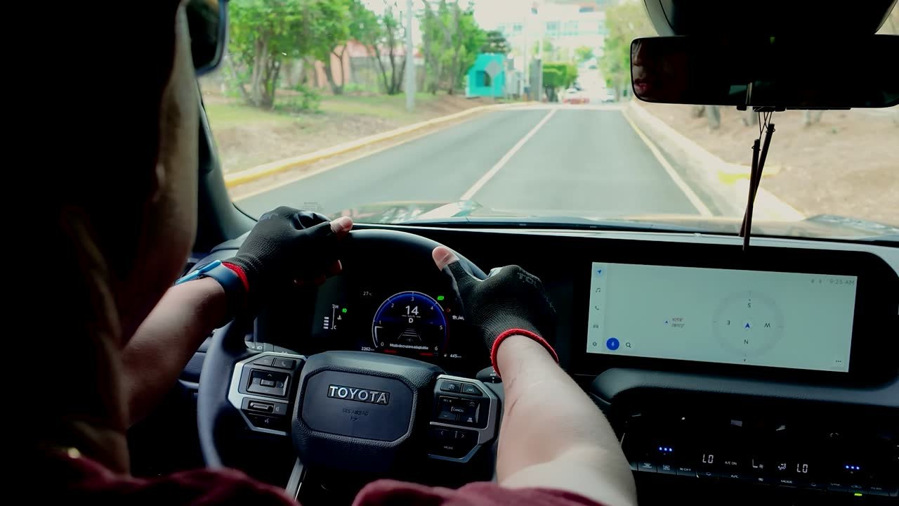 Conductor con guantes al volante del vehículo en marcha