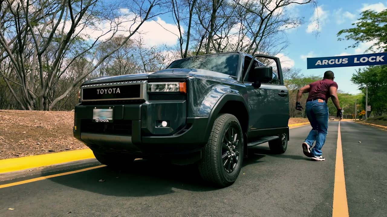 Un hombre se aleja corriendo de una camioneta detenida en la carretera, bajo un rótulo de Argus Lock